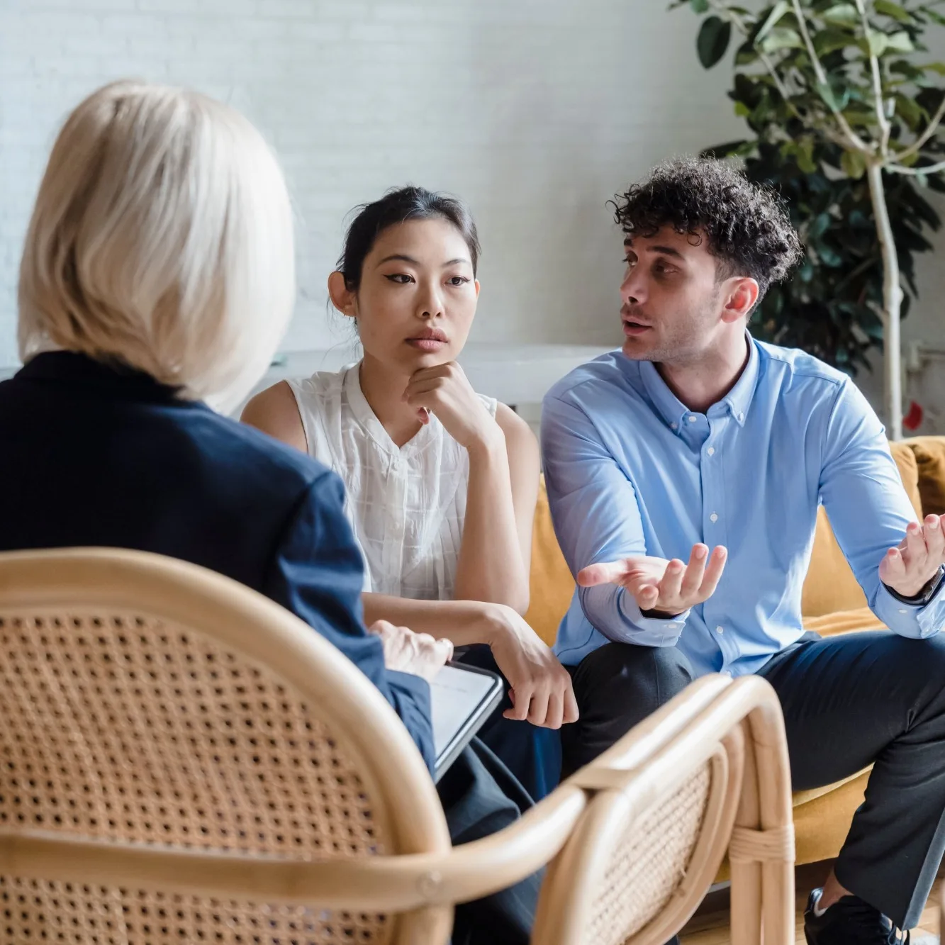 Fotografía: una psicóloga conversa con dos personas durante una entrevista clínica