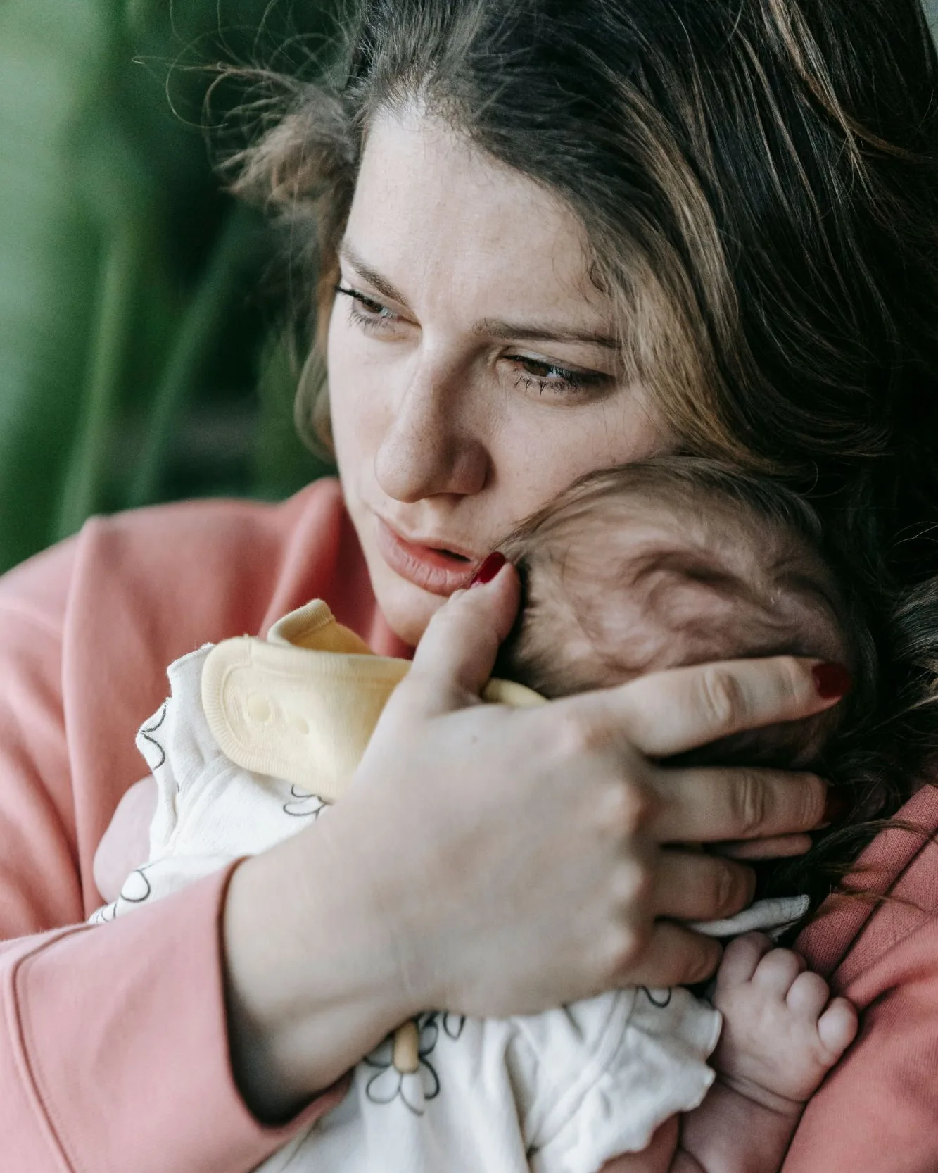 Fotografía: una madre sostiene en brazos a su bebé recién nacido con gesto de cansancio